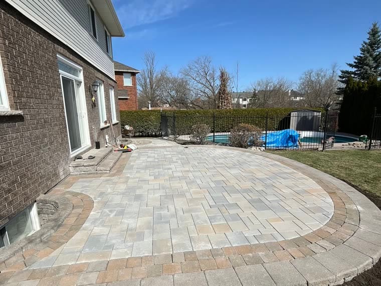 Backyard interlock patio and pool surround in blended grey pavers